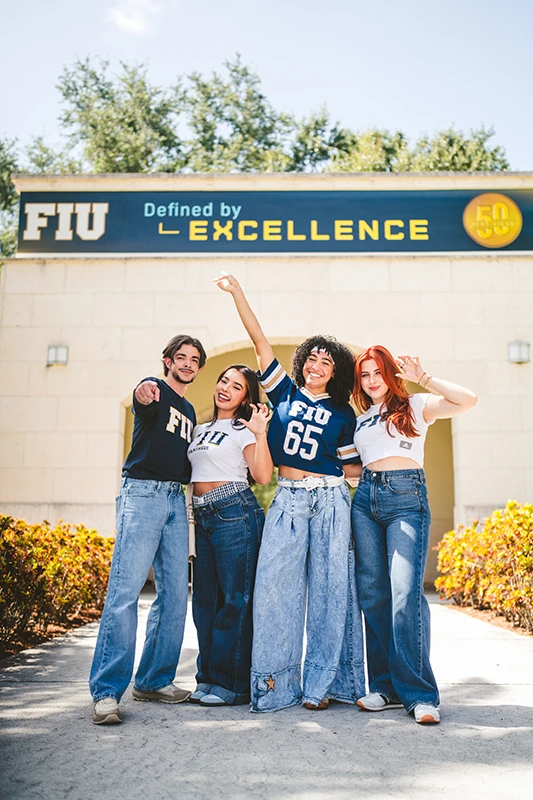 FIU students walk under a sign reading, "Defined by Excellence"
